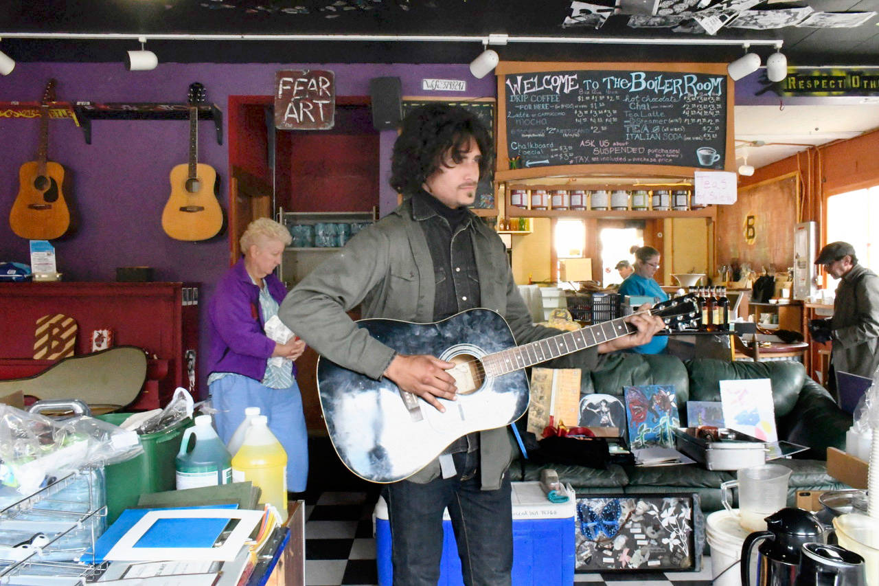 Torren Snyder plays one of the original guitars at the Boiler Room during a rummage sale to liquidate assets. The youth-oriented venue has closed its operations and the building will be sold. Another sale will be held Saturday. The board of directors plan to ask the youth in the community what they want the next version of the Boiler Room to become. (Jeannie McMacken/Peninsula Daily News)