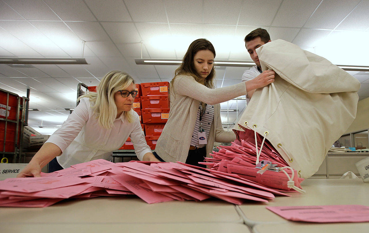 In this June 5 file photo, election workers Heidi McGettigan, left, Margaret Wohlford and David Jensen unload a bag of ballots brought in from a polling precinct to the Sacramento County Registrar of Voters office in Sacramento, Calif. (Rich Pedroncelli/The Associated Press)