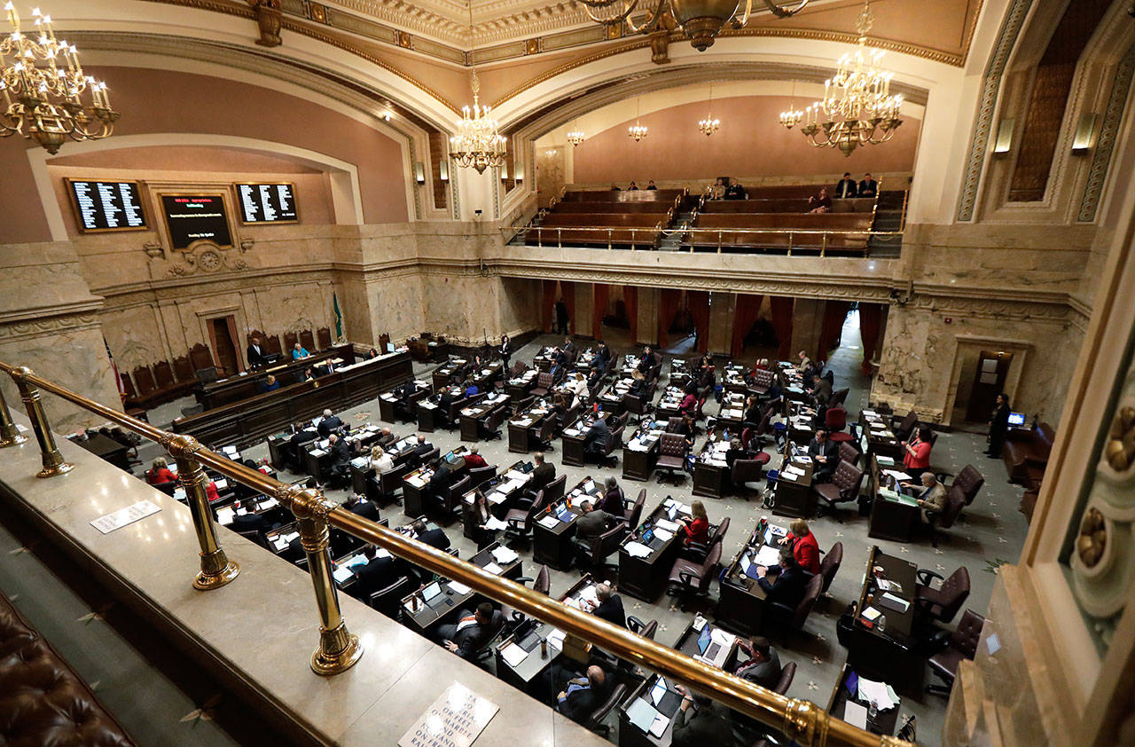 In this Feb. 7 file photo, state representatives work on the house floor at the Capitol in Olympia. (Ted S. Warren/The Associated Press)