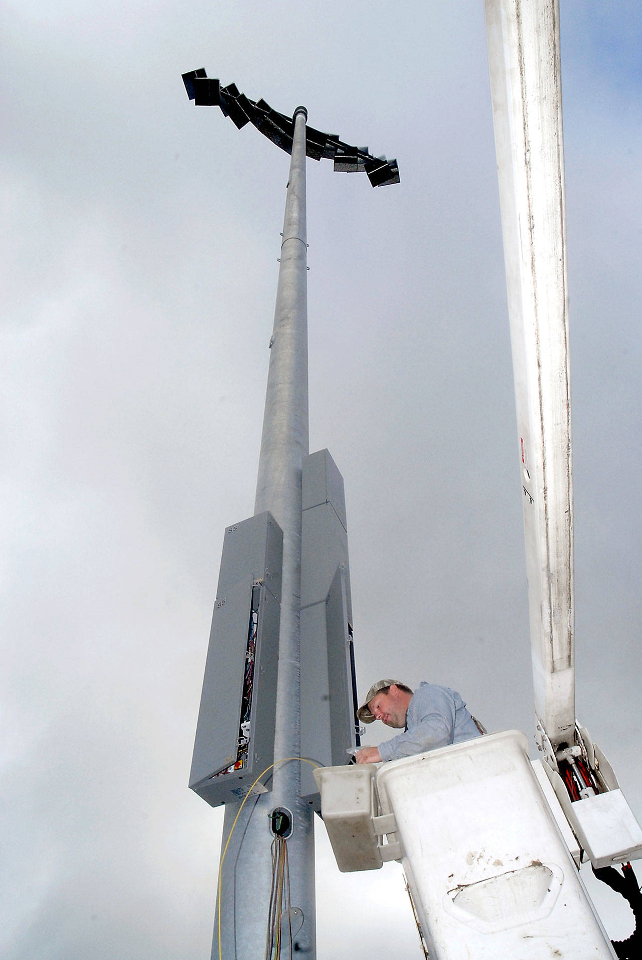 Keith Thorpe/Peninsula Daily News Ryan Johnson of Olympic Electric Co., of Port Angeles uses a lift bucket to connect wires in a new light tower at the Wally Sigmar Athletic Complex at Peninsula College in Port Angeles on Friday. The tower, one of five installed this week, will be used for nighttime events at the field, including college and possible high school play-off games, college athletic director Rick Ross said. Each tower supports banks of high-effiency LEDs to illuminate the playing surface