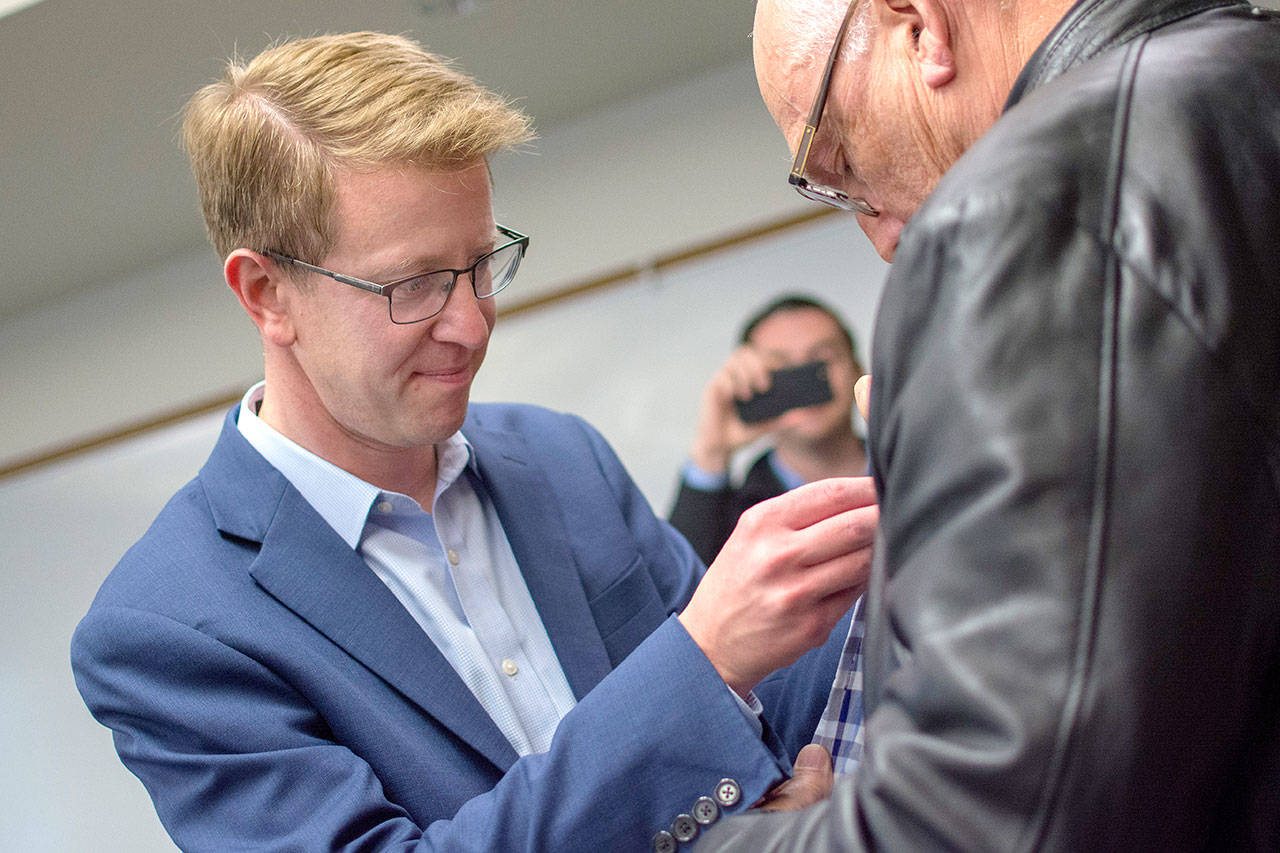 U.S. Rep. Derek Kilmer puts a pin on a veteran’s jacket during a pinning ceremony for Vietnam War era veterans in Port Ludlow Thursday evening. (Jesse Major/Peninsula Daily News)
