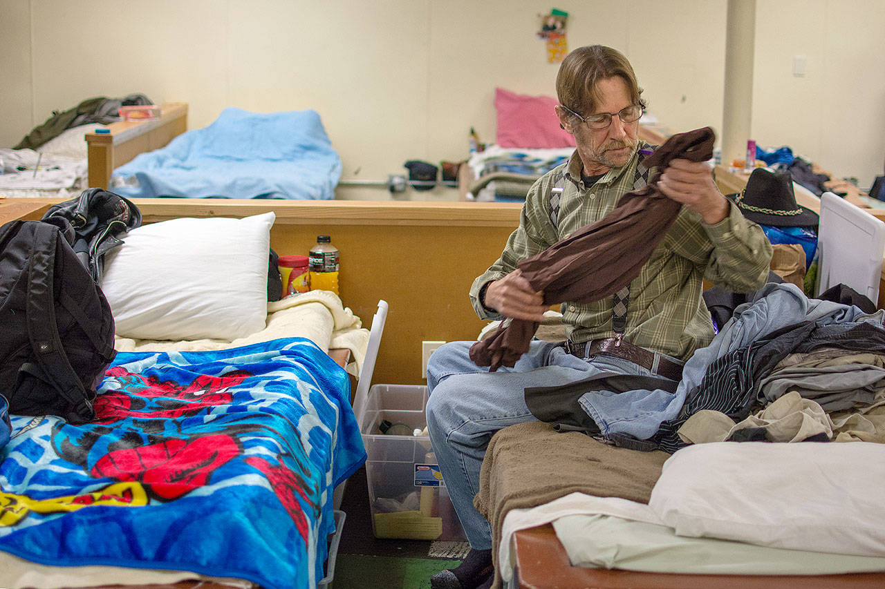 David Everett, a client at the Jefferson County Winter Shelter, tidies up his sleeping area before dinner. (Jesse Major/Peninsula Daily News)