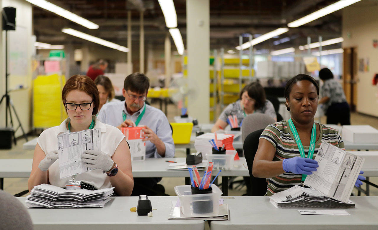 Emily Carlson, left, and Nikita Smith stack ballots from Washington state’s primary election Aug. 7 at King County Election headquarters in Renton. (The Associated Press)