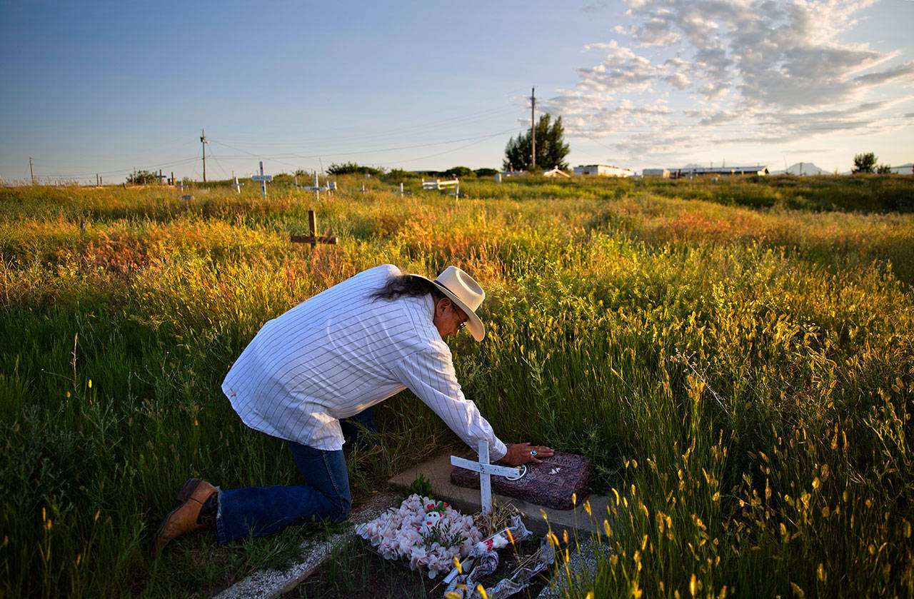 Kenny Still Smoking on July 14 touches the tombstone of his 7-year-old daughter, Monica, who disappeared from school in 1979 and was found frozen on a mountain, as he visits her grave on the Blackfeet Indian Reservation in Browning, Mont. A study released by a Native American nonprofit says numerous police departments in cities nationwide are not adequately identifying or reporting cases of missing and murdered indigenous women. (David Goldman/The Associated Press)