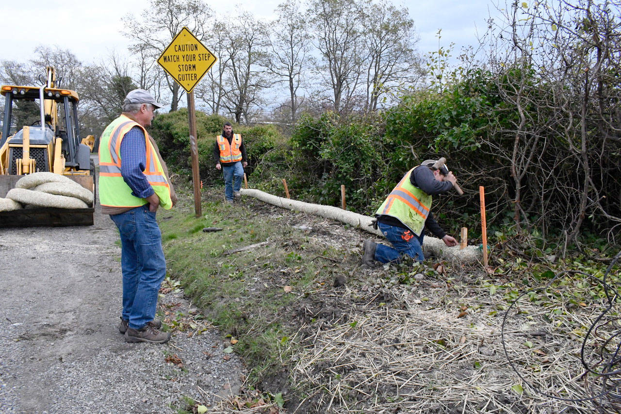 Port Townsend Public Works Inspector Scott Studeman takes a look at the initial work being done on the Jefferson Street sidewalk extension project. Foreman Jason White, center, and laborer Tyler Hamilton prepare the west side of the road with straw wattle for erosion control. The project is expected to be completed by the end of the year. (Jeannie McMacken/Peninsula Daily News)