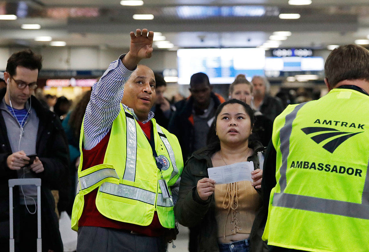 Anthony Navarro, an Amtrak Ambassador assisting travelers, helps a woman find the platform for her train Wednesday in New York’s Penn Station. (Mark Lennihan/The Associated Press)