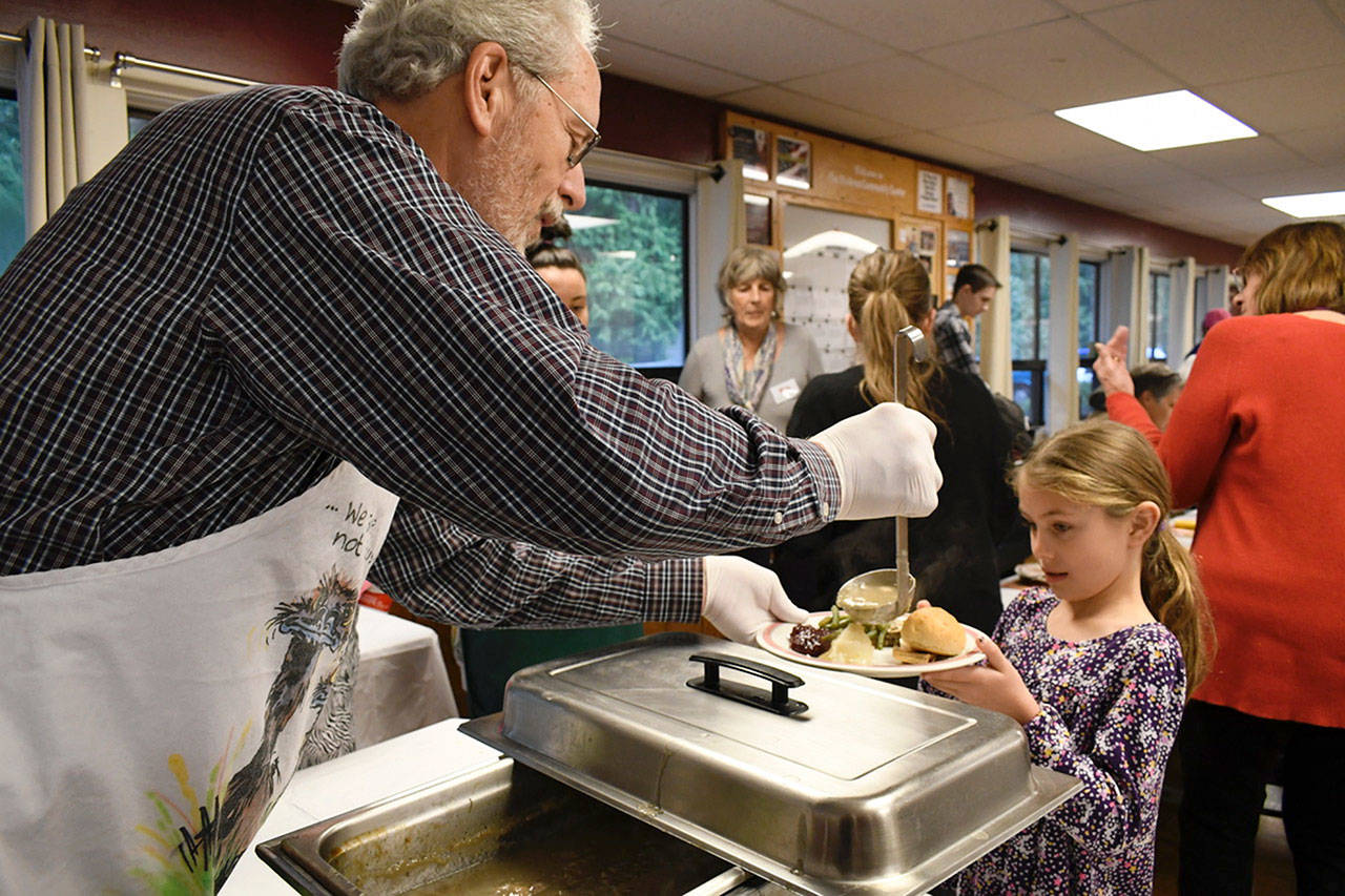 Steve Cordz of Port Townsend drizzles a finishing touch of gravy on 8-year-old McKenna Johnson’s Thanksgiving dinner at the Tri-Area Community Center’s holiday meal Thursday afternoon. (Jeannie McMacken/ Peninsula Daily News)