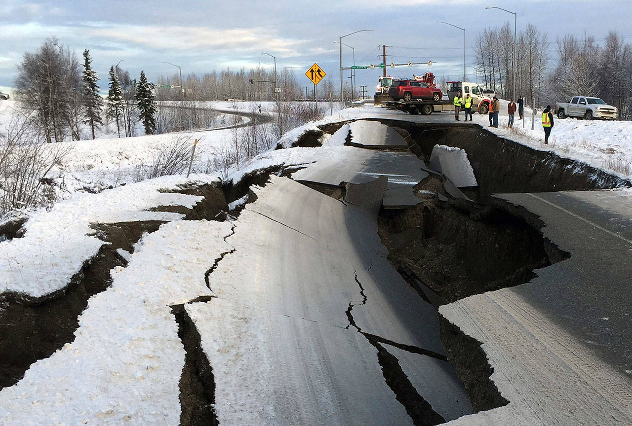 A tow truck holds a car that was pulled from on an off-ramp that collapsed during a morning earthquake Friday in Anchorage, Alaska. The driver was not injured attempting to exit Minnesota Drive at International Airport Road. (Mike Dinneen/The Associated Press)