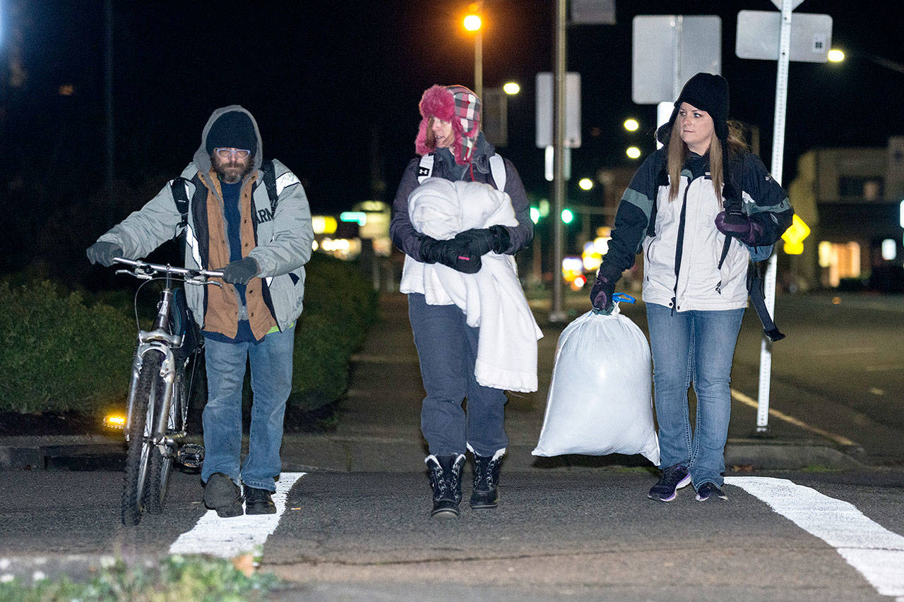 Mike Hollingsworth, Amy Miller, center, and Shenna Younger, right, walk towards the Salvation Army on Wednesday evening. (Jesse Major/Peninsula Daily News)