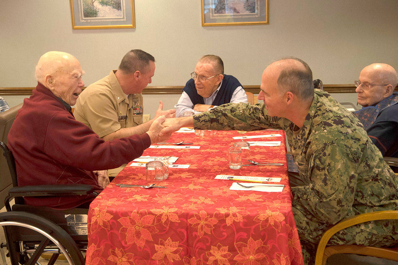 Rear Admiral Scott Gray, commander, Navy Region Northwest, shakes hands with Roy Carter, a Navy veteran and survivor of Pearl Harbor, during a luncheon with veterans at the Sherwood Assisted Living facility. (Mass Communication Specialist 2nd Class Wyatt L. Anthony/U.S. Navy)