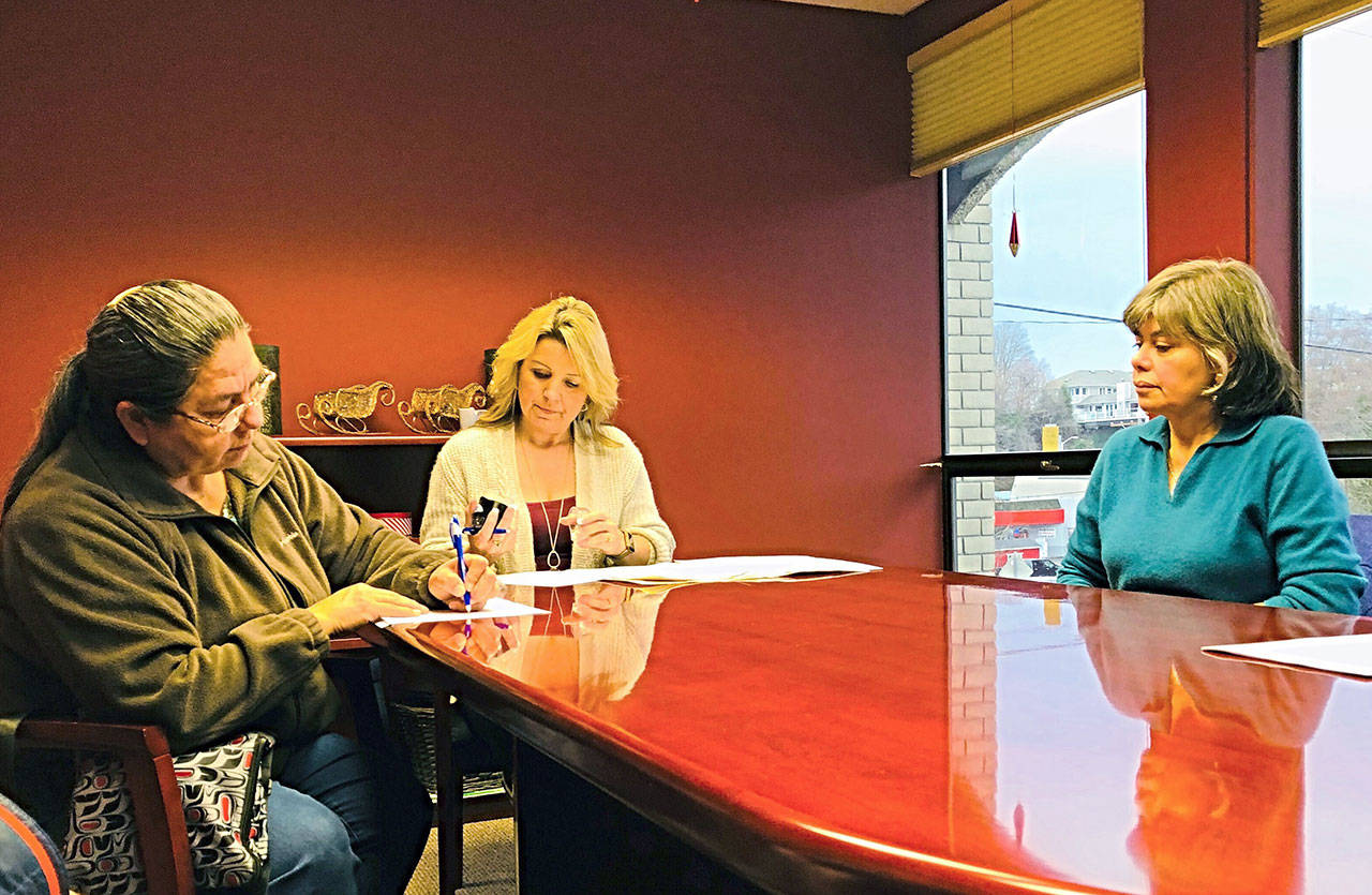 Lower Elwha Klallam Tribal Chairwoman Frances Charles, left, signs documents under which Port Angeles sold property to the tribe for a downtown hotel during closing procedures that included Mayor Sissi Bruch, right, and Clallam Title Escrow Assistant Jennifer Williams. (Lower Elwha Klallam Tribe)