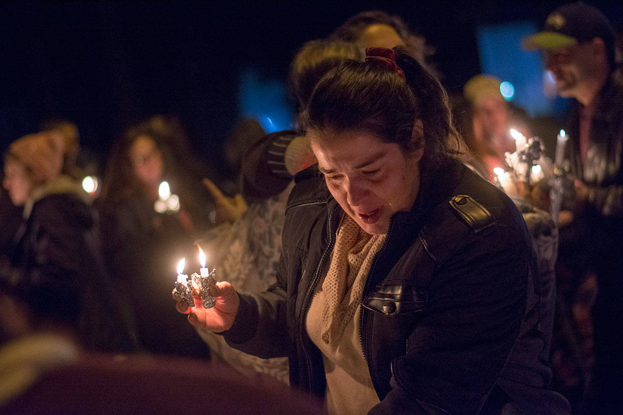 Sherry Emery looks over photos of her niece Tiffany May, May’s boyfriend Jordan Iverson and his father, Darrell Iverson, during a vigil in Port Angeles on Monday. May and the Iversons were shot and killed possibly on Dec. 26, according to law enforcement officials. (Jesse Major/Peninsula Daily News)