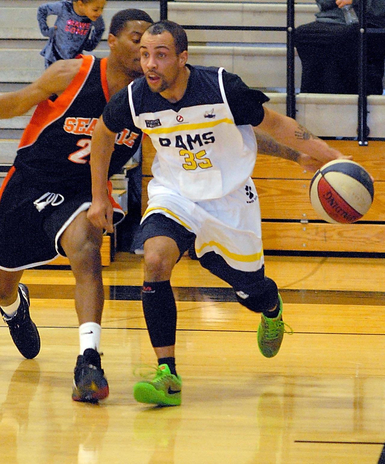 Keith Thorpe/Peninsula Daily News Port Angeles Rams’ Kenny Meier, front, drives to the lane as Seattle Mountineers’ Jawan Stepney attempts to knock the ball away during second quarter play on Saturday night at Peninsula College in Port Angeles.