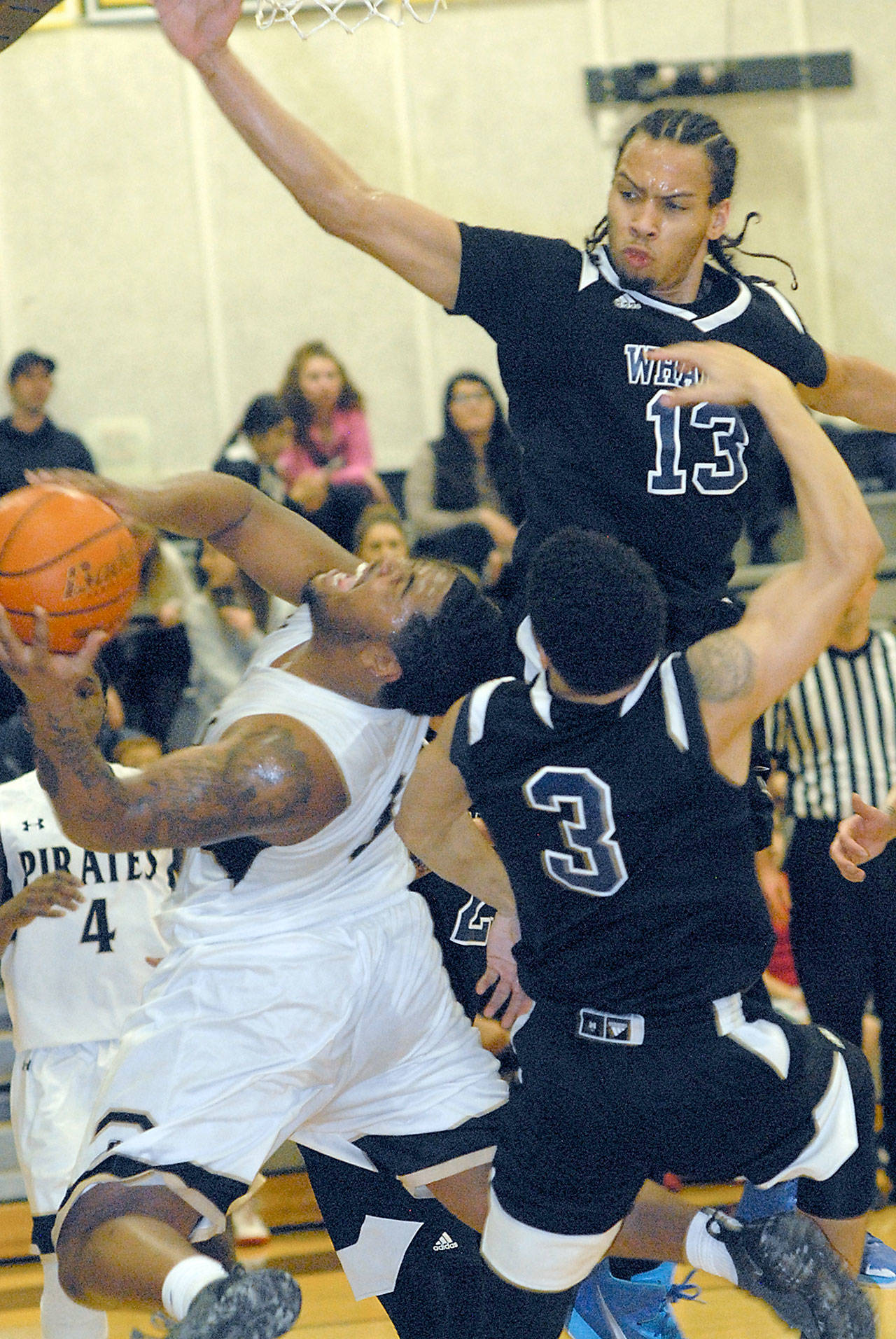 Keith Thorpe/Peninsula Daily News Peninsula’s Davien Harris-Williams, left, falls back to take a shot as Whatcom’s Isaac Reason, top, and Donavan Sellgren attempt to block in the closing moments of the first half on Wednesday in Port Angeles.