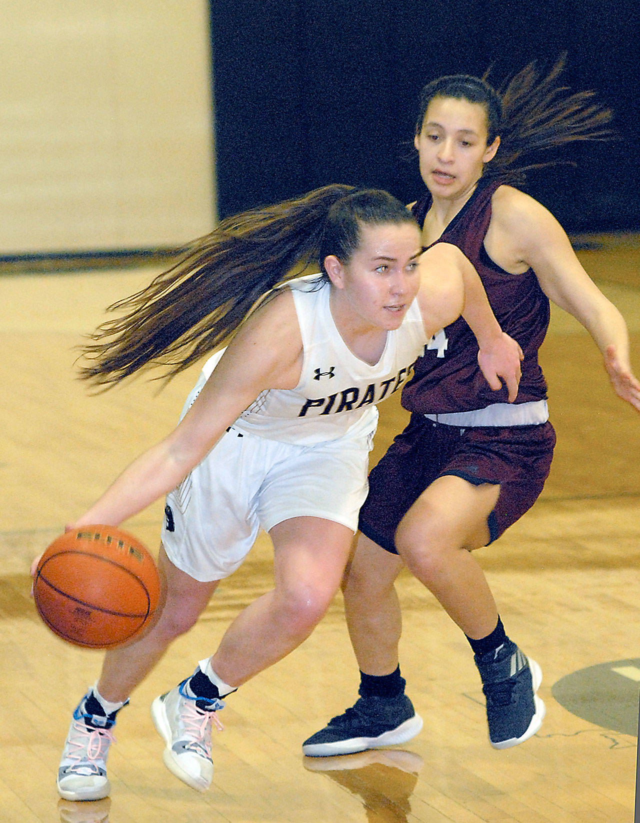 Keith Thorpe/Peninsula Daily News Peninsula’s Ashlynn Sharp, left, squeezes around Whatcom’s Annaleis Reyes on Wednesday night in Port Angeles.