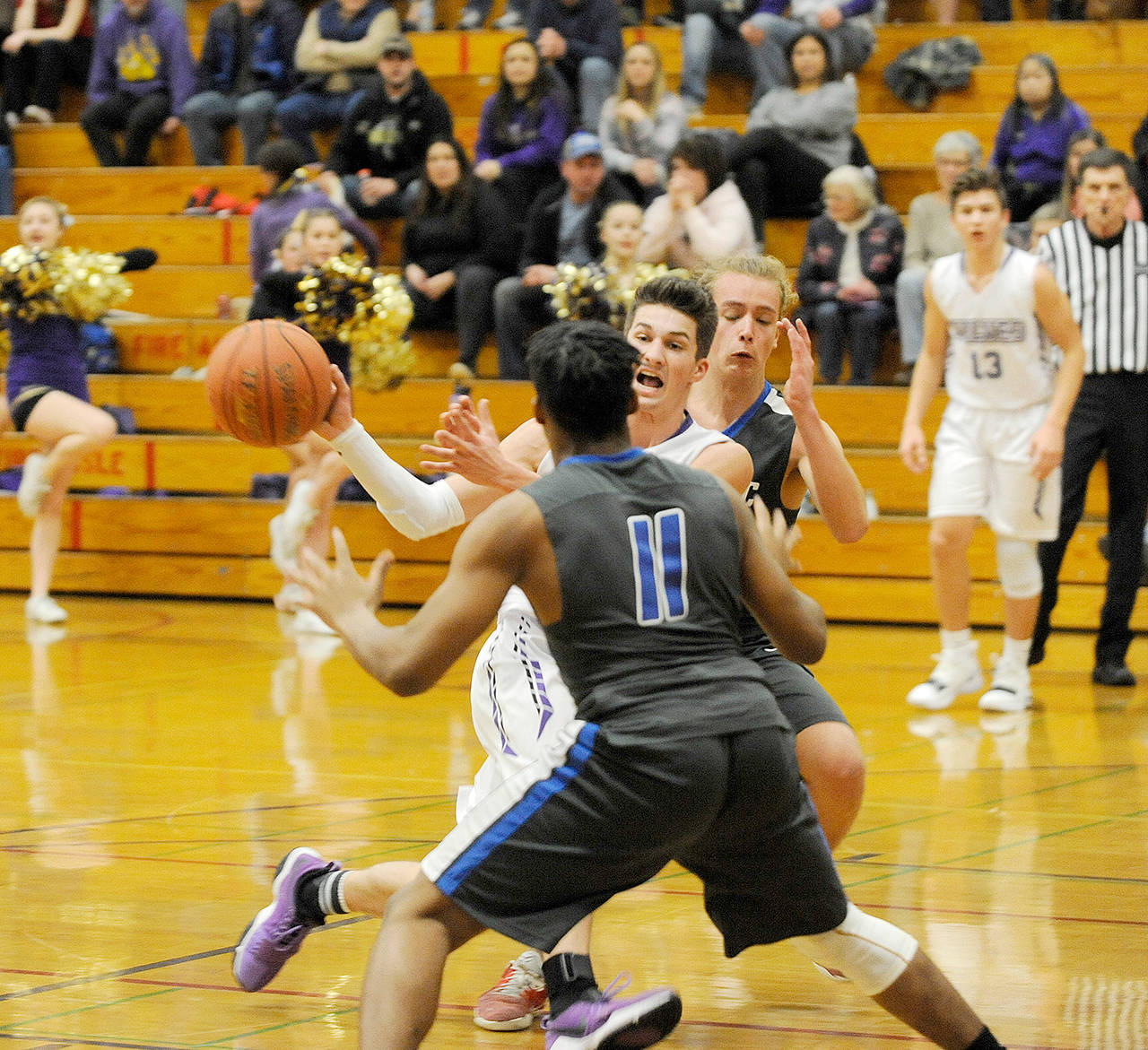 Michael Dashiell/Olympic Peninsula News Group Sequim’s Nate Despain, center, passes the ball while defended by Olympic’s Darrelle White (foreground) and Brady Nelson during the Wolves’ 51-47 win over the Trojans.