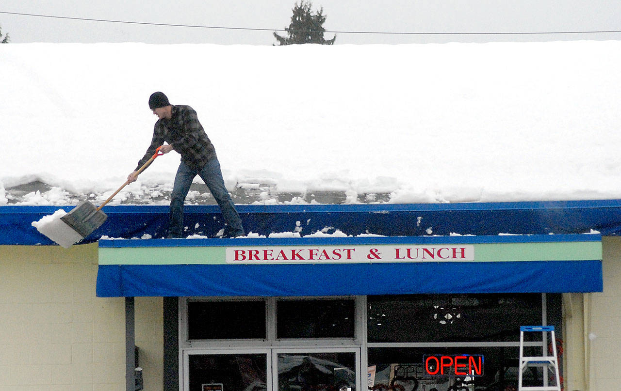 Casey Balch of Port Angeles shovels snow from the roof of Shirley’s Cafe on South Lincoln Street in Port Angeles on Tuesday. Restaurant owner Sheri Mackrow said she feared a repeat of the snowstorm of 1996 — when heavy snow followed by rain led to roof collapses from the weight of the combined slush — so she enlisted the help of her son to reduce the load. (Keith Thorpe/Peninsula Daily News)