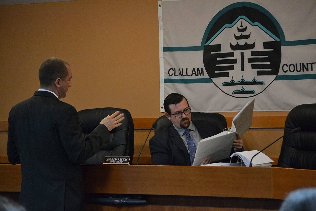Andrew Reeves, Clallam County hearing examiner, accepts a packet of complaints from Alex Sidles, attorney for Concerned Atterberry Neighbors, on Feb. 7. Nearby residents of a proposed 66-unit manufactured home park oppose multiple elements of the plan, including its impact on fish habitat, traffic and much more. (Matthew Nash/Olympic Peninsula News Group)