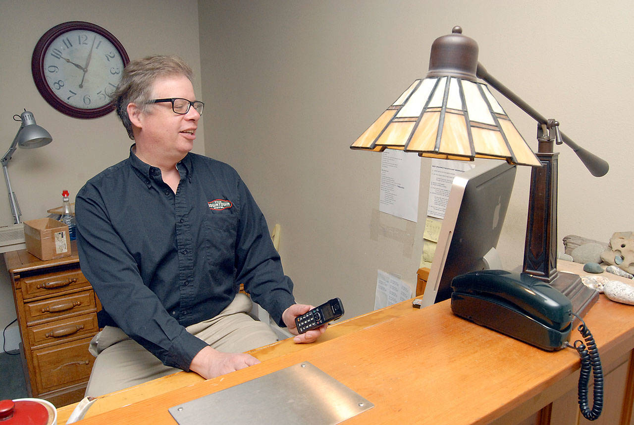Tim Chamberlain, general manager of the Downtown Hotel and principal partner of the family-owned company that owns the Port Angeles business, sits at the front desk in the hotel lobby on Saturday. (Keith Thorpe/Peninsula Daily News)
