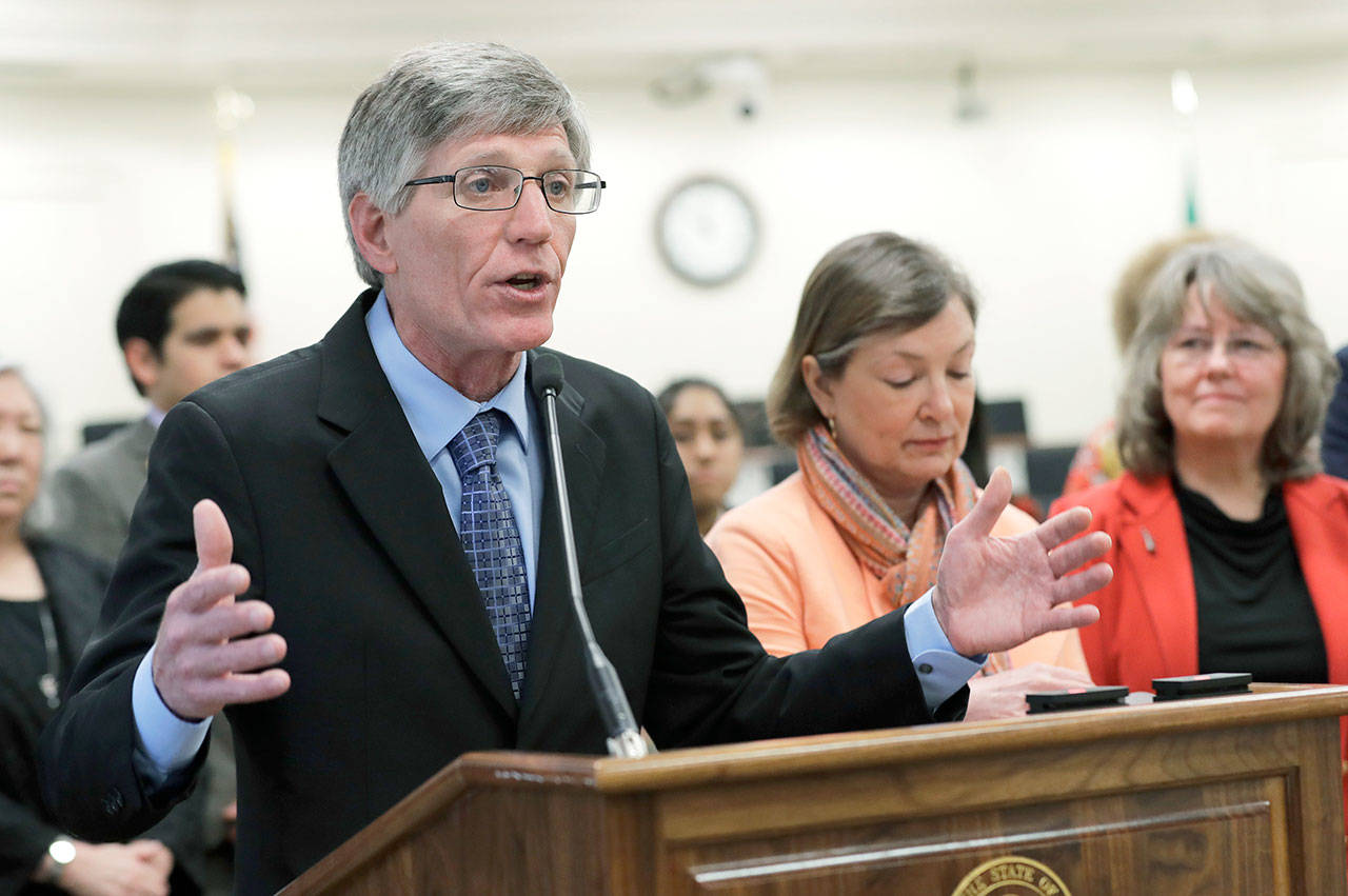 Rep. Timm Ormsby, D-Spokane, left, talks to reporters Monday. The House Democrats unveiled a two-year state budget proposal Monday that seeks $1.4 billion in new revenue, including a new capital gains tax on the sale of high-value stocks and bonds. (AP Photo/Ted S. Warren)