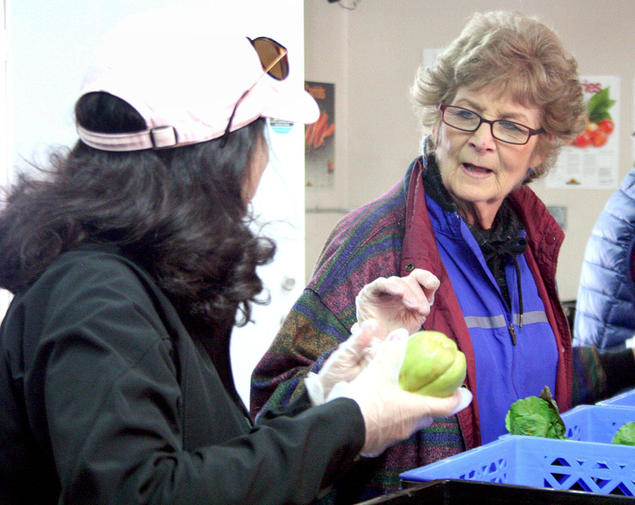 Sandra Largaespada, left, from Food Lifeline of Seattle, helps Tri-Area Food Bank volunteer Barbara Smith on Wednesday in Port Hadlock. Largaespada is the manager of the Grocery Rescue program that works with area stores and repackages goods for homeless shelters, food banks and meal programs. (Brian McLean/Peninsula Daily News)
