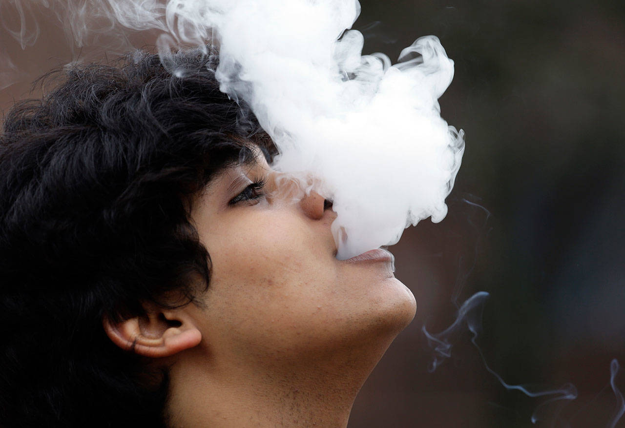 In this 2016 photo, a man who declined to be identified blows out a cloud of smoke as he puffs on a small pipe outside at Seattle Central College in Seattle. (Elaine Thompson/The Associated Press)
