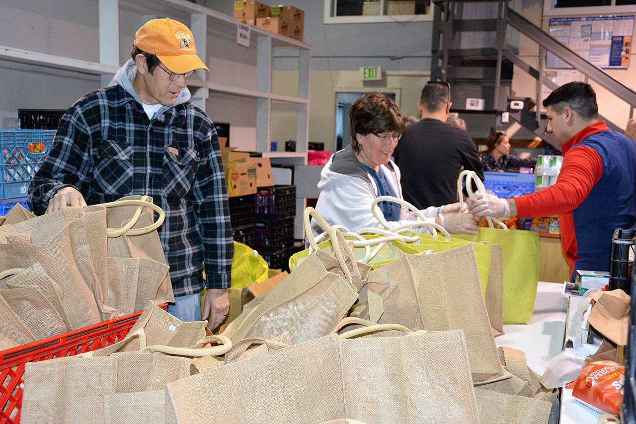 Fran Howell, center, and several members of the Olympic Kiwanis prepare “break bags” for parents to pick up. The bags of groceries will help feed Port Angeles children over spring break this week. (Patsene Dashiell/Port Angeles School District)