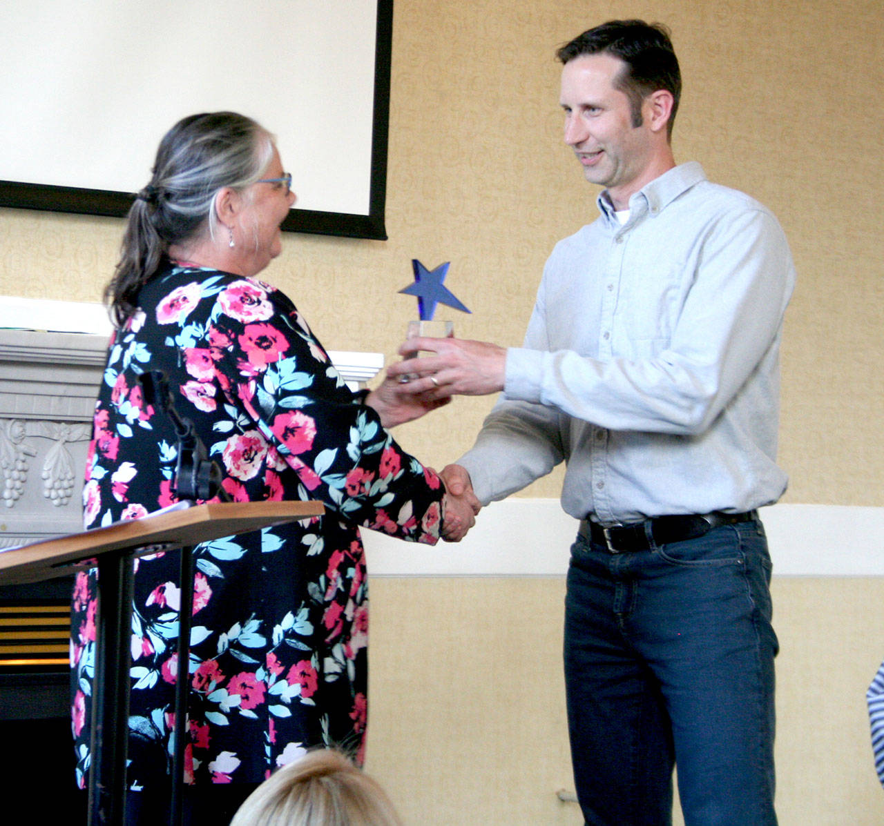 Hans Frederickson, owner of Frederickson Electric, accepts the Business Leader of the Year award from Betsy Davis, the executive director of the Northwest School of Wooden Boatbuilding, during the Chamber of Jefferson County luncheon Sunday at the Old Alcohol Plant in Port Hadlock. (Brian McLean/Peninsula Daily News)
