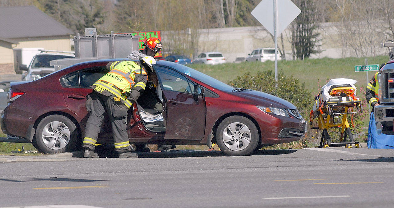 Clallam County Fire District 2 Assistant Chief Dan Huff, front, looks in at the victim of a collision involving three vehicles at the intersection of U.S. Highway 101 and Kolonels Way near the Port Angeles Walmart Supercenter on Tuesday. (Keith Thorpe/Peninsula Daily News)
