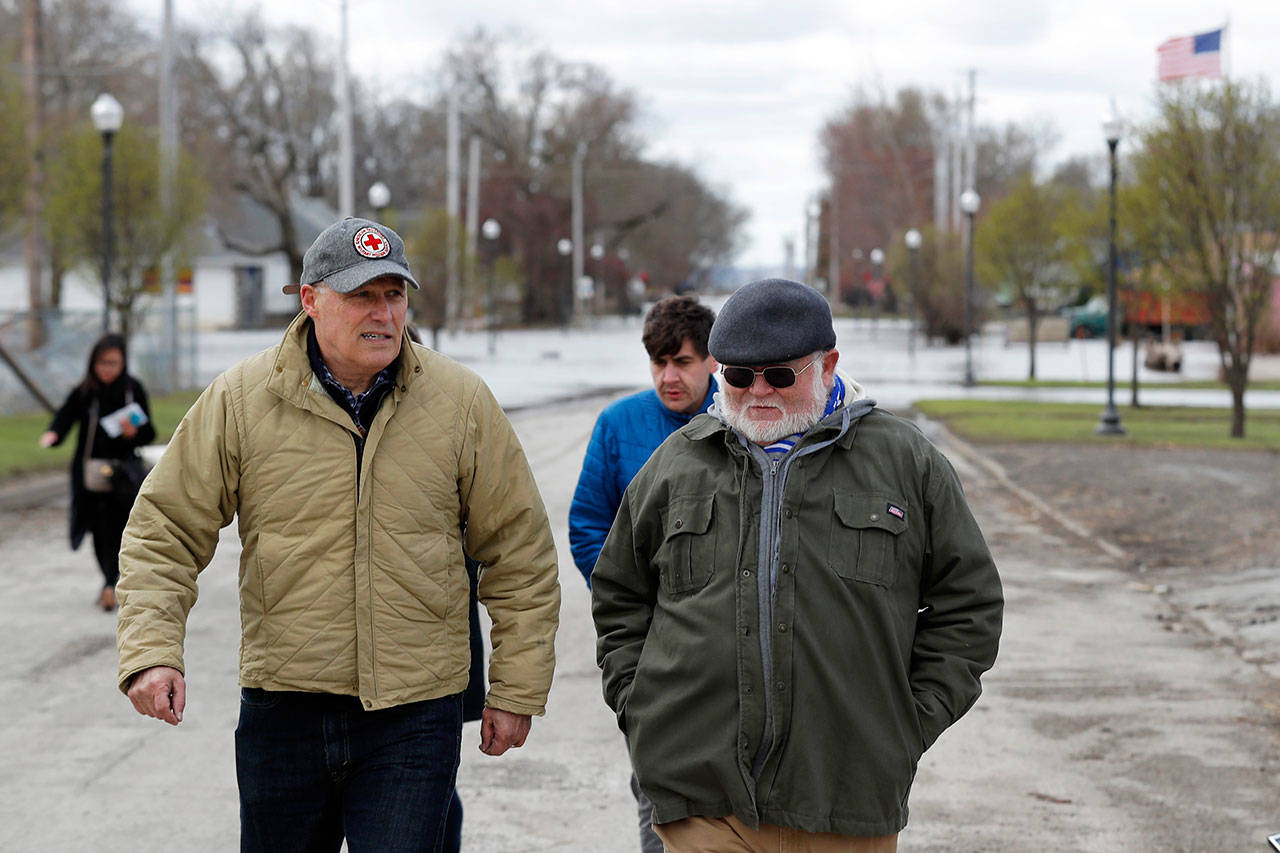 Gov. Jay Inslee, left, walks with climate analyst John Davis of Hamburg, Iowa, while touring flood damage Friday, April 12 in Hamburg, Iowa. (Charlie Neibergall/The Associated Press)