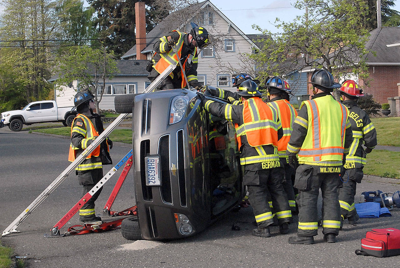 Port Angeles firefighters work to gain access to the driver of a car involved in a two-car collision at the intersection of Ninth and Oak streets in Port Angeles on Wednesday morning. No one was injured in the wreck, but firefighters had to chop through the windshield to free the driver who was trapped inside. (Keith Thorpe/Peninsula Daily News)