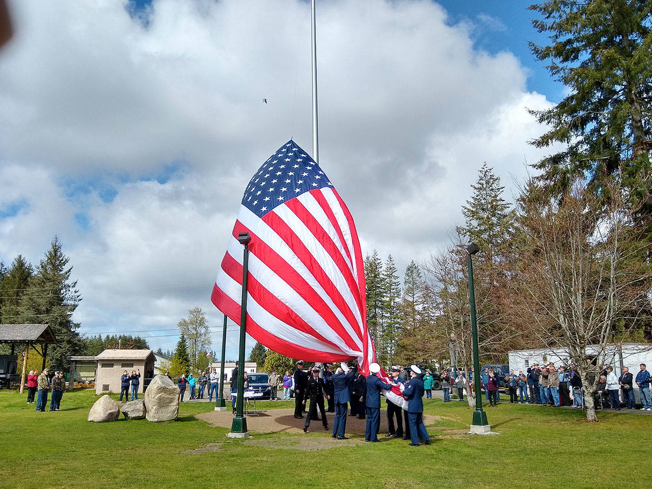 A new, and very large, American flag was the center of the dedication ceremony for the new flagpole at Tillicum Park in Forks. (Zorina Barker/for Peninsula Daily News)