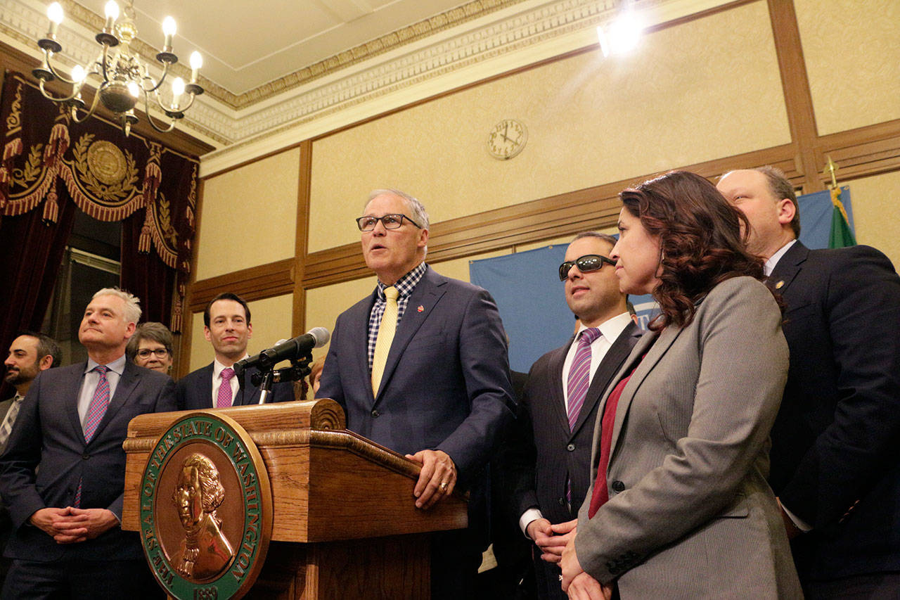 Gov. Jay Inslee, surrounded by Democratic lawmakers from the Senate and House, talks to the media early Monday following the Legislature adjourning its 105-day legislative session in Olympia. Lawmakers passed a new, two-year budget before adjourning for the year. (Rachel La Corte/The Associated Press)