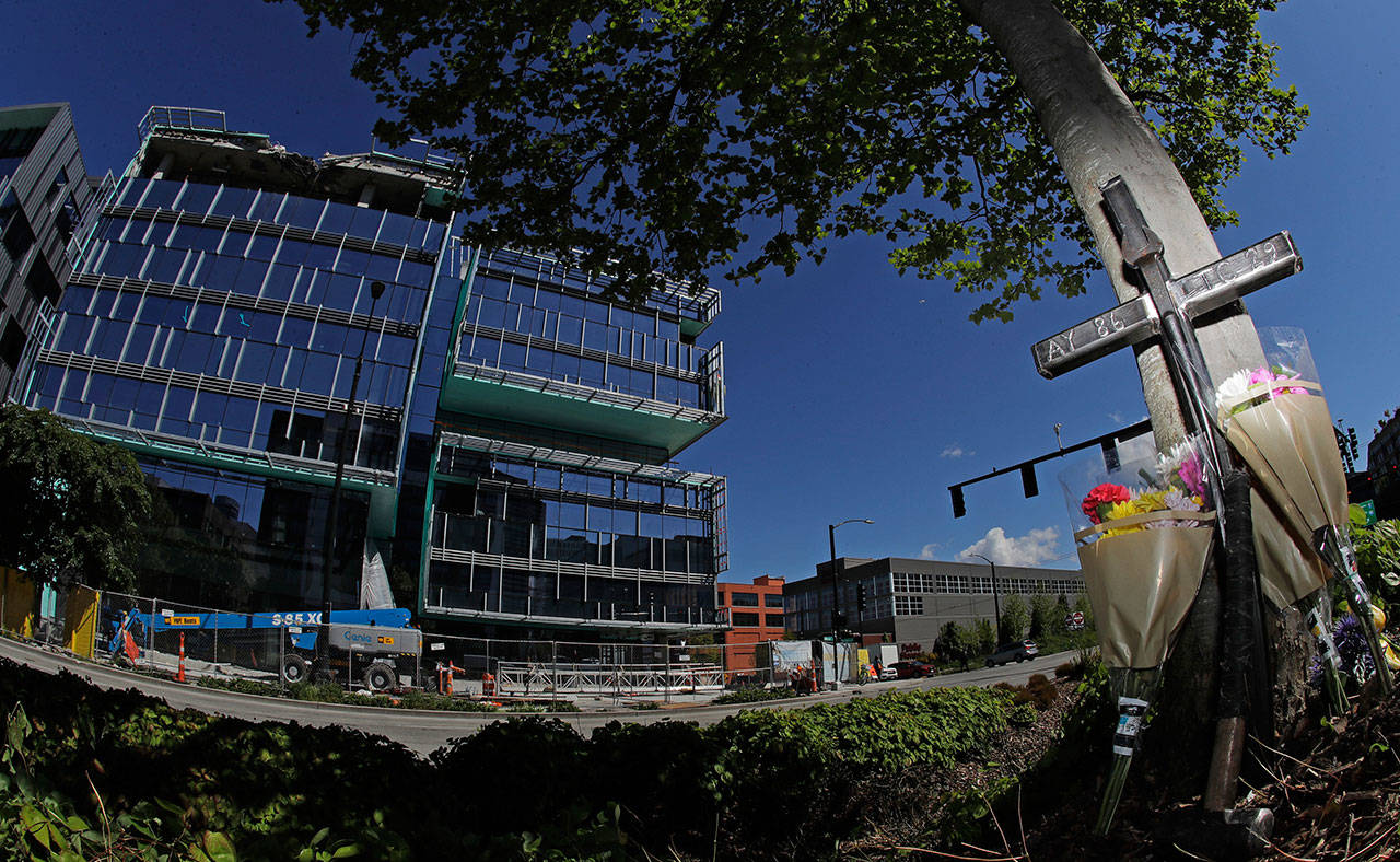 An iron cross bearing the numbers of Ironworkers Local union chapters from Portland and Seattle stands next to flowers on Monday at a memorial on a median across the street from where a construction crane collapsed and fell Saturday, killing four people, two of whom were ironworkers. (Ted S. Warren/The Associated Press)