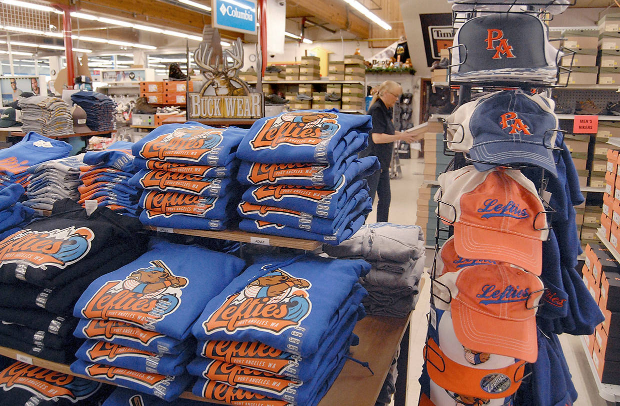 Port Angeles Lefties merchandise sits on display at Swain’s General Store in Port Angeles as shoe department employee Marci Dotson stocks shelves in the background Tuesday. (Keith Thorpe/Peninsula Daily News)