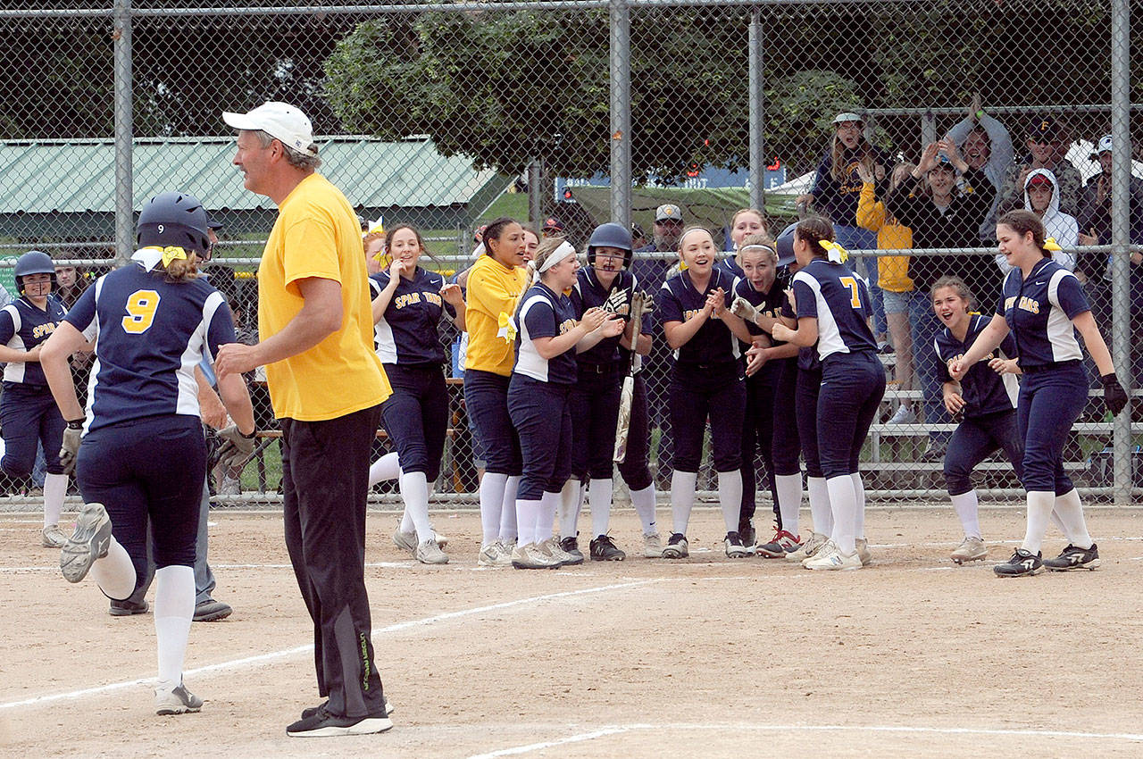Forks’ Chole Leverington (9) heads for home after knocking the ball over the left field fence as the Spartans defeated Lynden Christian 5 to 0. Awaiting at home plate are a group of happy Spartans while head Coach Jr. Dean looks on. (Lonnie Archibald/for the Peninsula Daily News)