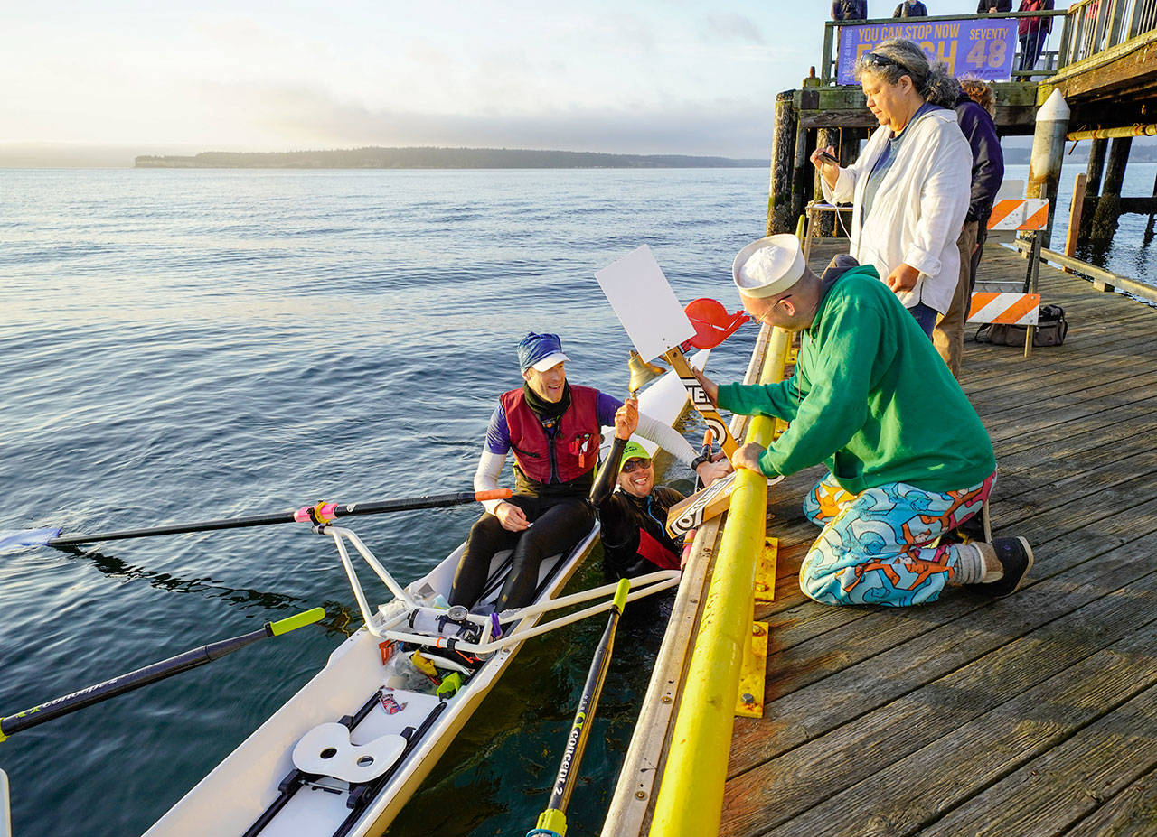 Thiago Silva, from Brazil, took a dive into the cold waters of Port Townsend Bay and swam under the boat to ring the bell announcing that he and rowing partner Greg Spooner, from Bainbridge Island, won the 2nd annual Seventy48 boat race that started in Tacoma at 7 p.m. Friday. The pair rowed their two-man scull the 70-mile distance in 10 hours and 49 minutes. The race was open to only human-powered watercraft. (Steve Mullensky/for Peninsula Daily News)