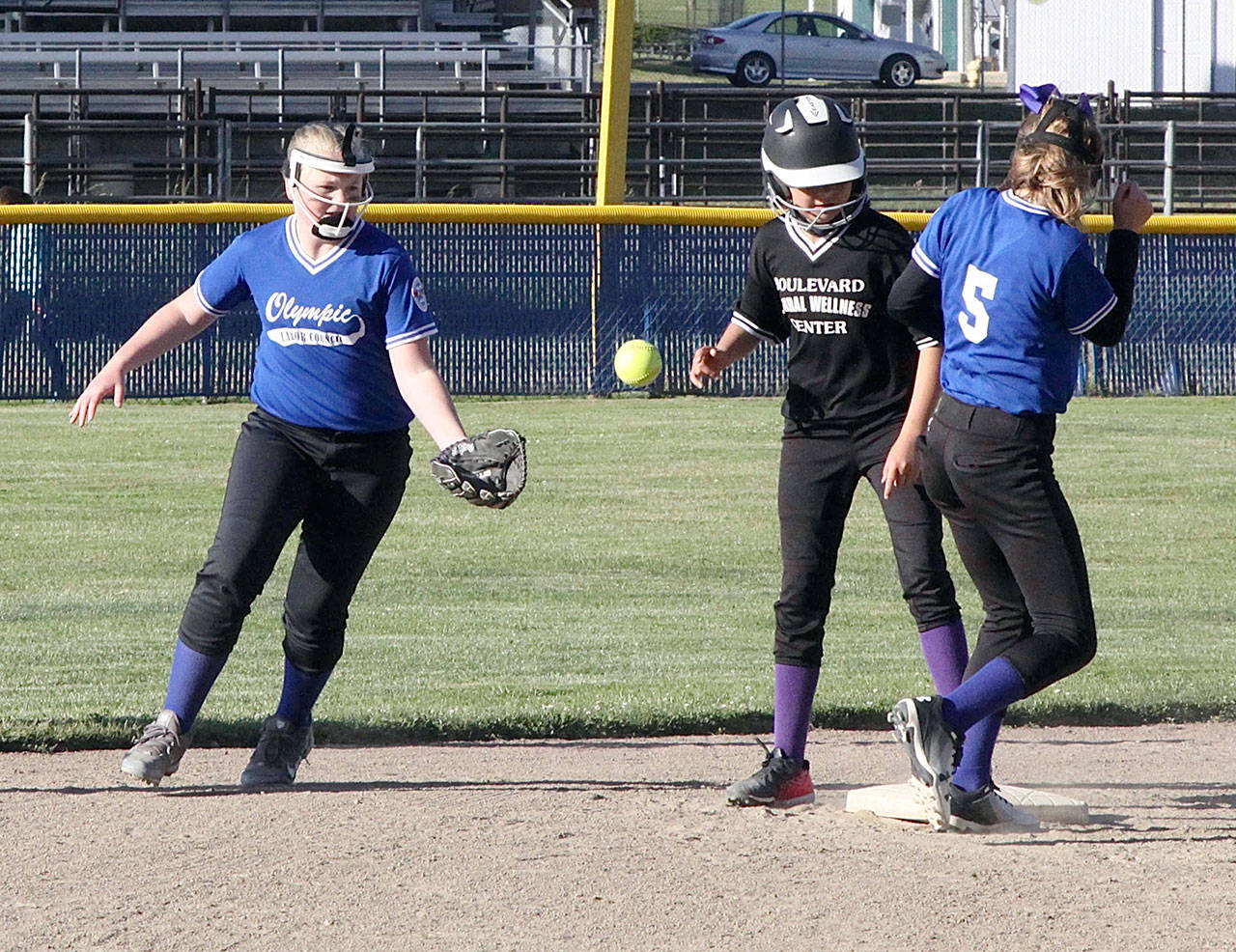 <strong>Dave Logan</strong>/for Peninsula Daily News Boulevard Wellness’ Malena Marquez stands up safely after stealing second base while Olympic Labor Council’s Violet Mills (5) and her teammate Evie Seeyle attempt to field the ball.