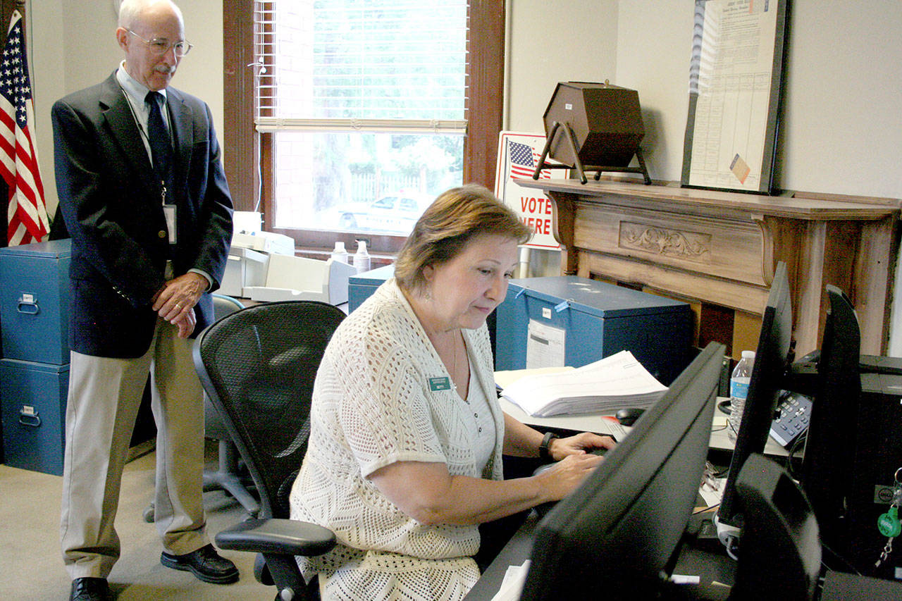 Jefferson County Election Coordinator Betty Johnson verifies signatures of a petition submitted by the Committee for Port Accountability on Tuesday morning at the county auditor’s office. David Neuenschwander of Quilcene, left, is a leader of the committee, which is seeking to ask the Port of Port Townsend to ask voters if they should approve a 20-year property tax levy. The verification process might last through Friday, Johnson said. (Brian McLean/Peninsula Daily News)