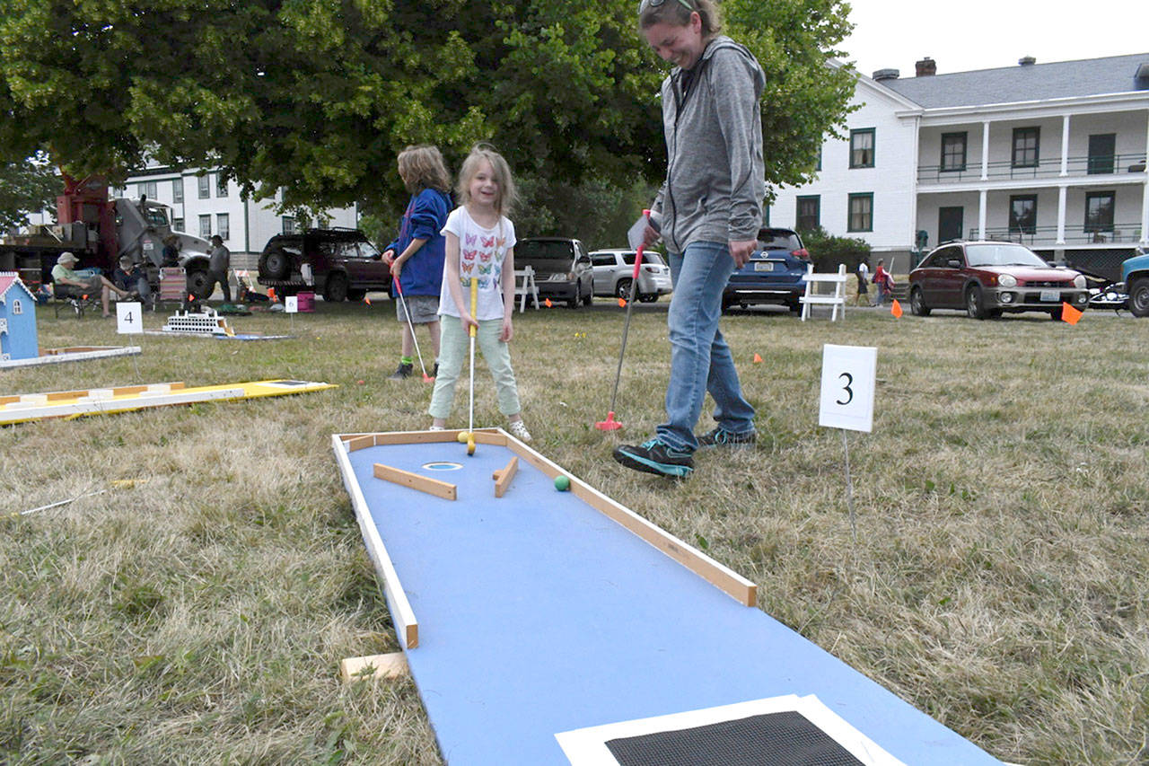 Bobbie McEachran teaches her daughter, Teagan, to play mini-golf during the 2018 Old School 4th of July at Fort Worden’s parade grounds in Port Townsend. (Jeannie McMacken/Peninsula Daily News)