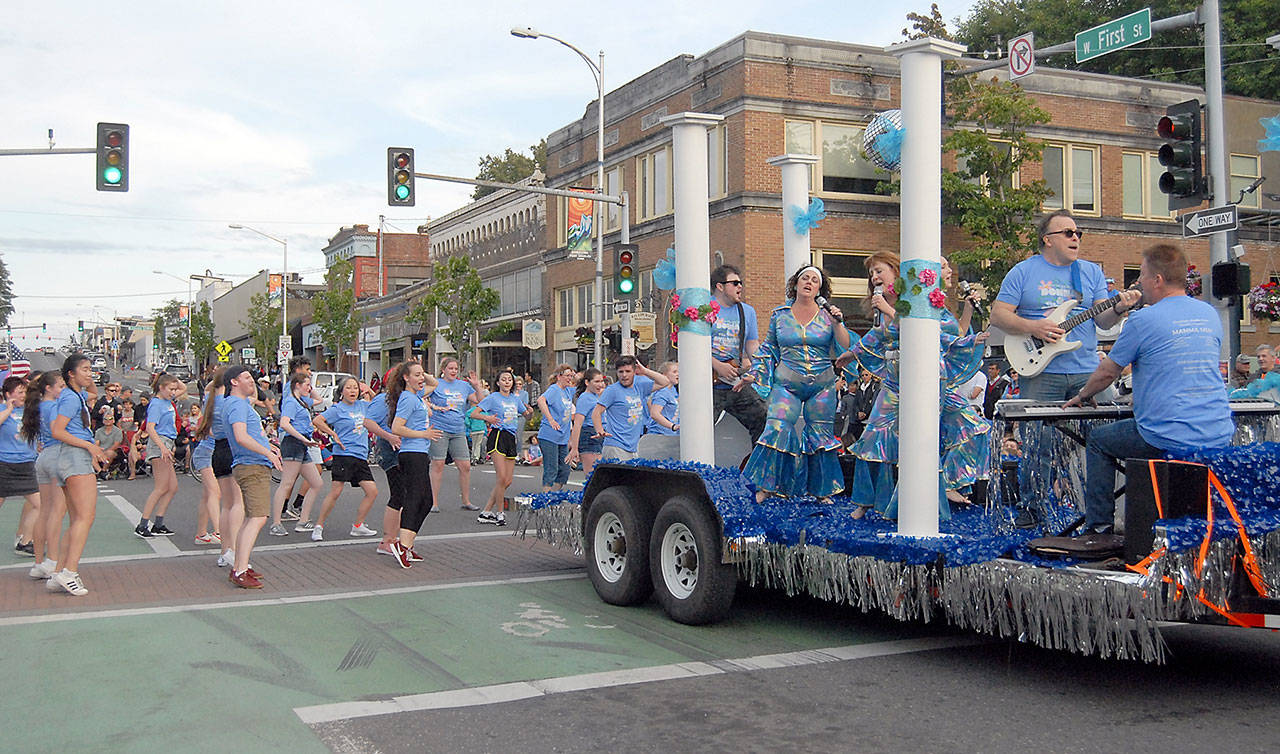 The cast of “Mamma Mia” sings and dances with the Ghostlight Productions float during the Port Angeles Independence Day Parade. (Keith Thorpe/Peninsula Daily News)