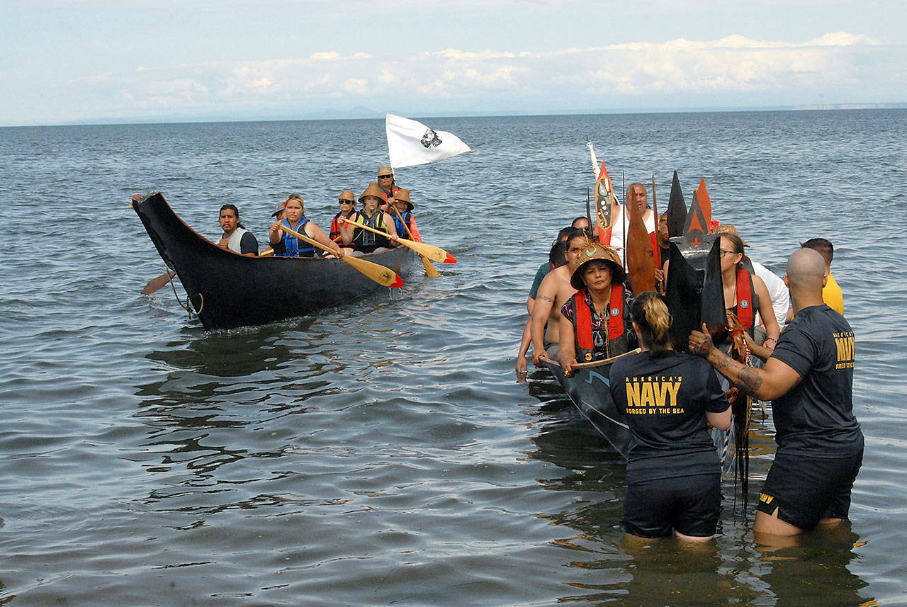 A canoe from Mowachaht First Nation, left, pulls up next to a Makah tribal canoe during Tuesday’s 2019 Canoe Journey landing at Jamestown Beach, territory of the Jamestown S’Klallam Tribe. (Keith Thorpe/Peninsula Daily News)