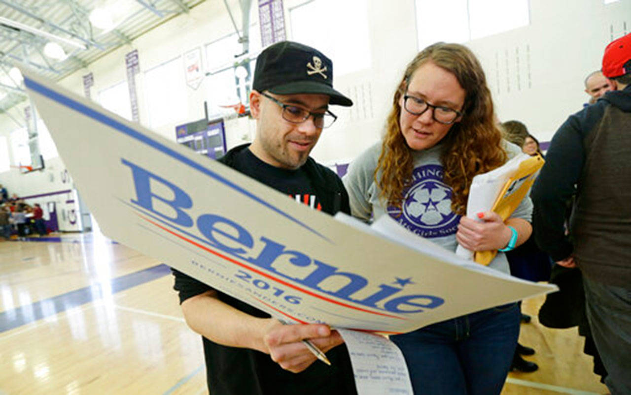 In this March 26, 2016, file photo, Stuart Huntoon, left, and Stephanie Edmisson hold a sign supporting Democratic presidential candidate Sen. Bernie Sanders as they attend a precinct group during a Democratic caucus at Garfield High School in Seattle. (Ted S. Warren/The Associated Press, File)