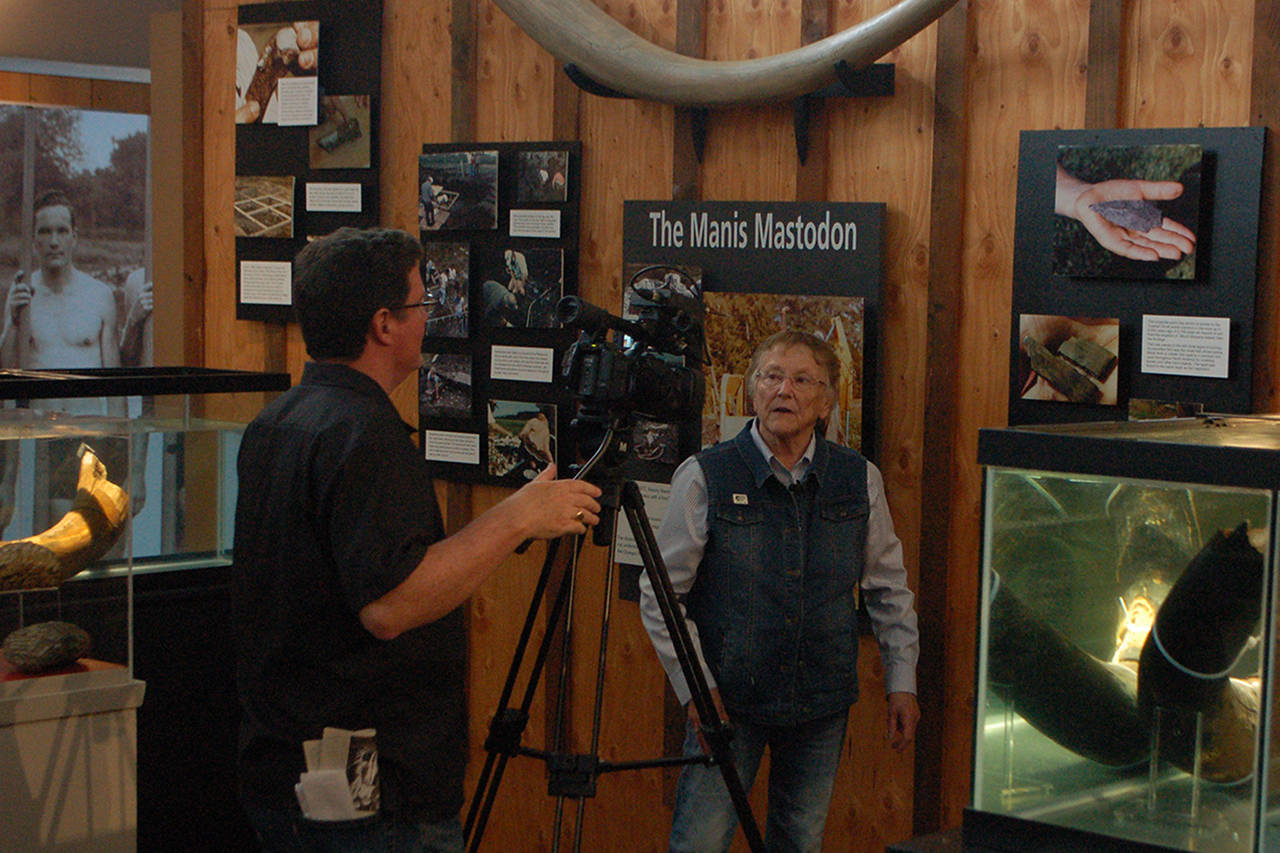 Clare Manis Hatler, center, discusses the Manis Mastodon in the new Sequim Museum Arts building. She was being interviewed by KBTC associate producer Chris Anderson, left, for a segment of the “Northwest Now” web program. (Conor Dowley/Olympic Peninsula News Group)