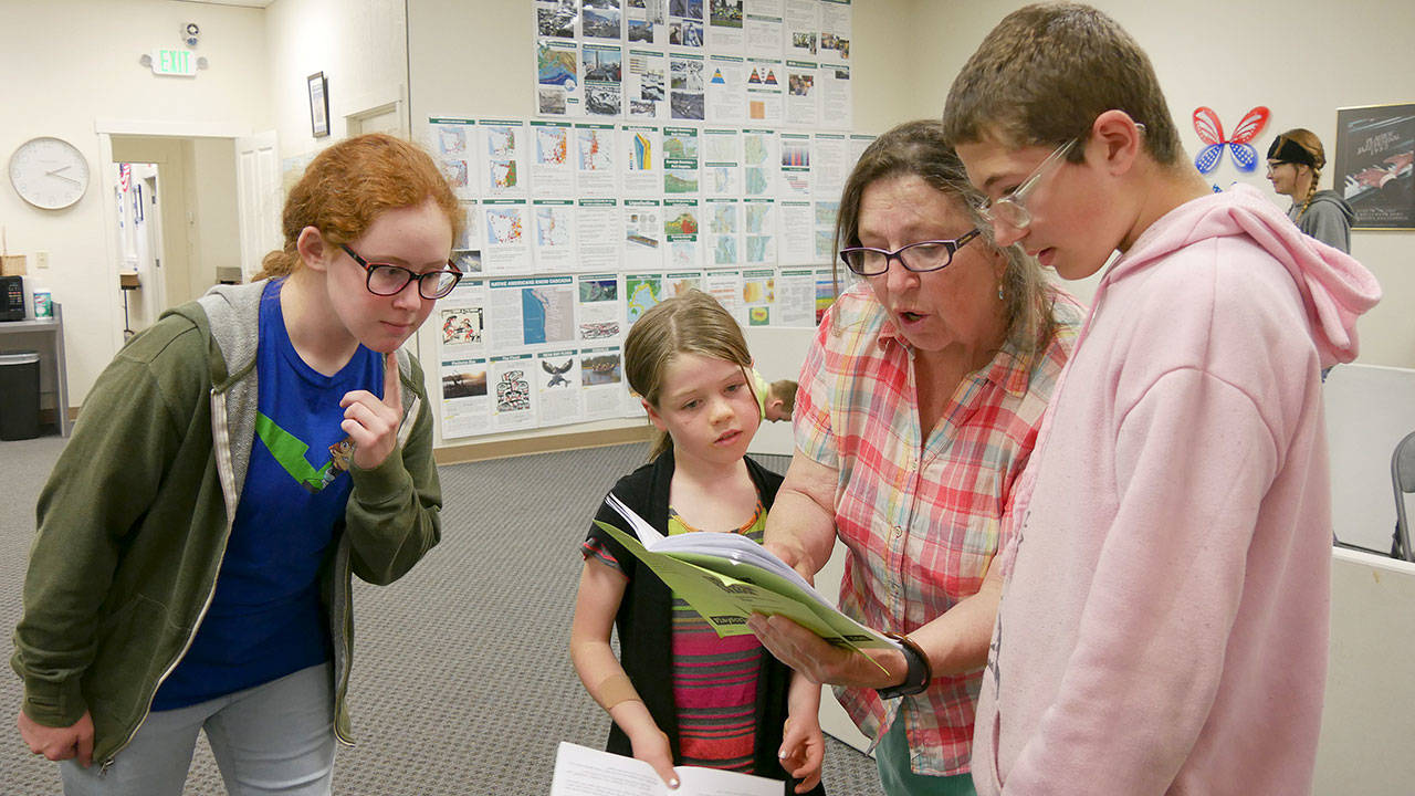 From left, Grayce Houle, Maia Brewer, director Bonne Smith and Hunter Halverson work on lines for the upcoming Olympic Theatre Arts production of “The Reluctant Dragon.” (Olympic Theatre Arts)