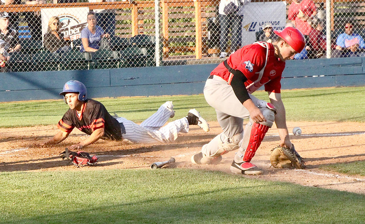 Dave Logan/for Peninsula Daily News Port Angeles’ Brad Altomarie slides into home safely as Victoria catcher Tyson Hays juggles the throw from the outfield.