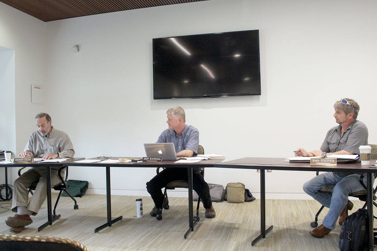 PUD Board of Commissioners Kenneth Collins, left, Jeff Randall, and Dan Toepper discuss the removal of a fee associated with service that the PUD no longer provides. (Zach Jablonski/Peninsula Daily News)