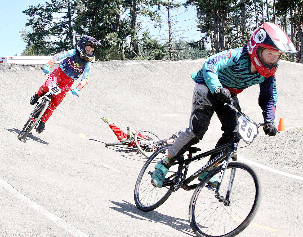 Anthony Jones (25) of Port Angeles is in the lead over Peyton Calhoun (69) of Port Orchard while taking a spill is Jesse Campos of Tacoma, who got up and finished the race. Jones limped home third at the Washington State BMX finals held Sunday at Lincoln Park. Jones won the 11 Cruiser race. More than 1,000 riders competed in races this weekend at Lincoln Park. (Dave Logan/for Peninsula Daily News)