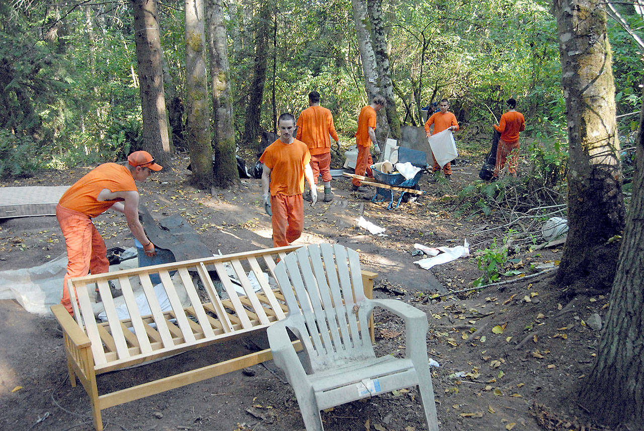 Members of the Clallam County Sheriff’s Office Chain Gang gather trash and belongings for disposal during a sweep Tuesday of homeless camps on state Fish & Wildlife land in the Morse Creek Valley east of Port Angeles. (Keith Thorpe/Peninsula Daily News)