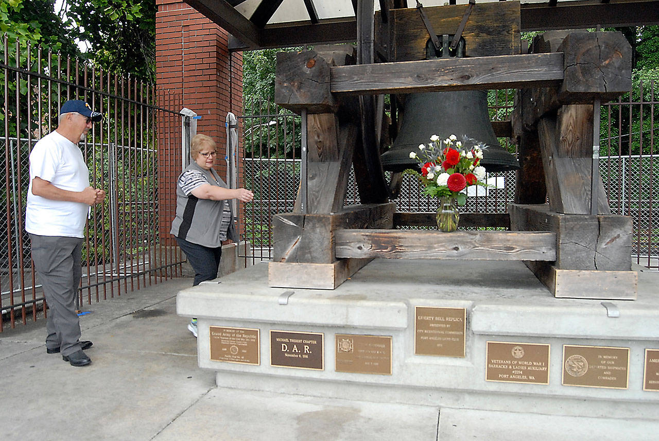 Former Port Angeles Mayor Karen Rogers, right, points out damage to the Liberty Bell replica inflicted by vandals as Clallam County Veterans Association President Gary Velie, left, looks on at Veteran’s Memorial Park on Friday in Port Angeles. (Keith Thorpe/Peninsula Daily News)